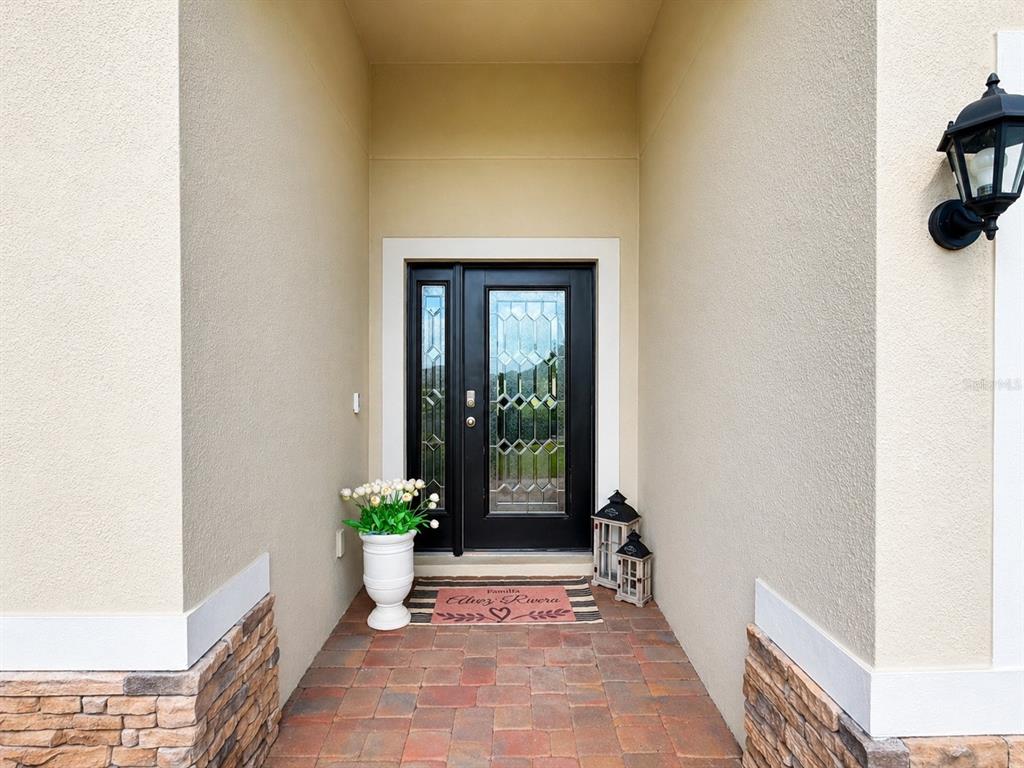 A front entryway features a black glass-paneled door, a potted plant, and a welcome mat — 6860 CAMEO DR, GRANT VALKARIA, FL
