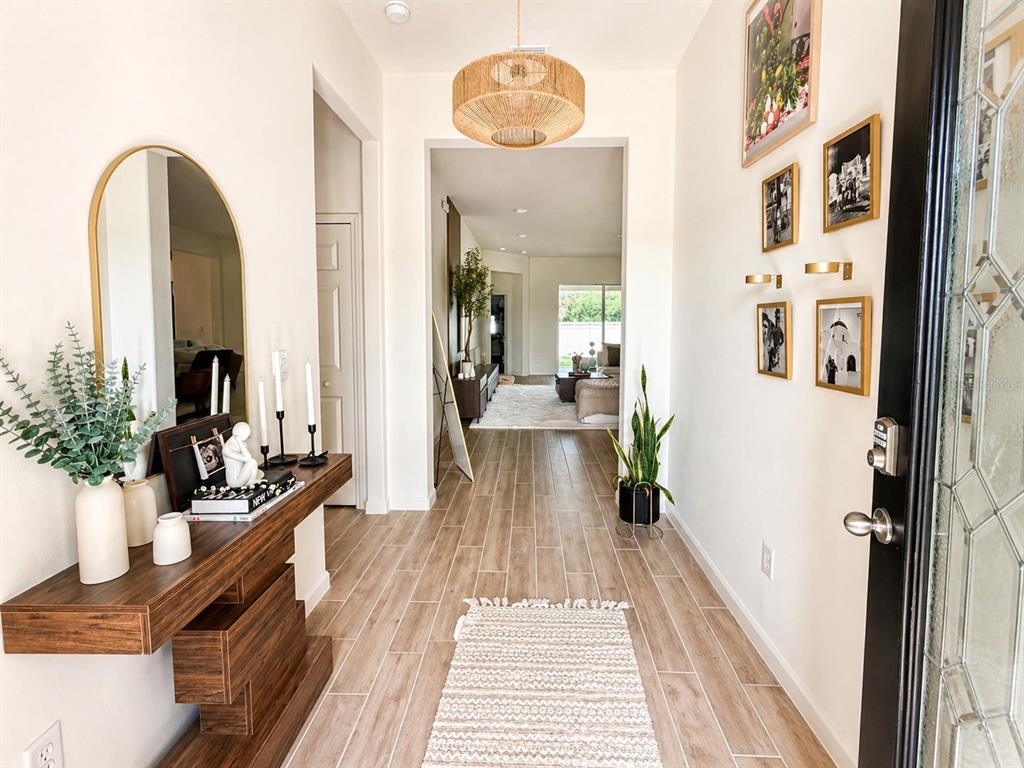 A bright entryway features wood-look tile flooring, a floating console table, and a woven pendant light — 6860 CAMEO DR, GRANT VALKARIA, FL