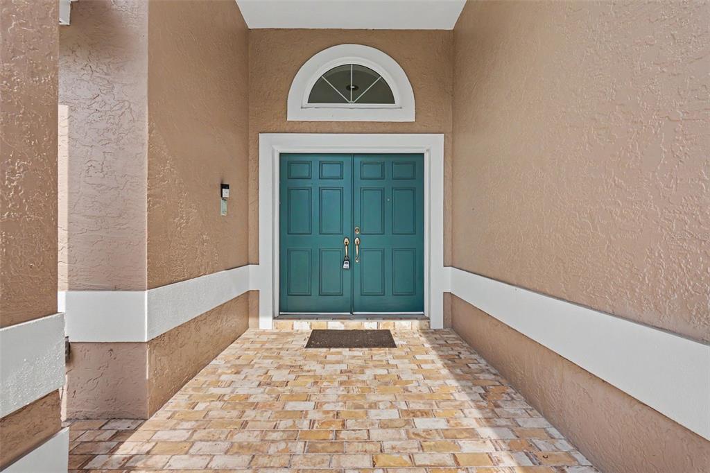 A teal double front door with a semi-circular window sits under a covered entryway — 2782 SCOBEE DRIVE, PALM HARBOR, FL