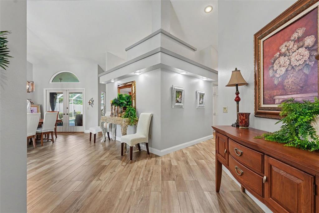 A bright entryway features light wood-look flooring, a central architectural column, and a wooden console — 2782 SCOBEE DRIVE, PALM HARBOR, FL
