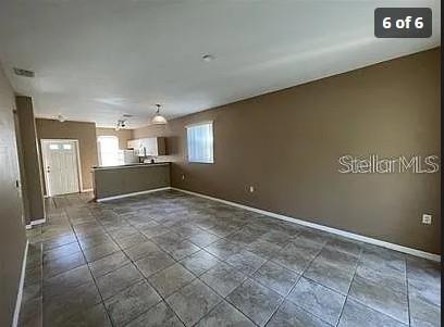 An open-concept living area features tan walls, gray tile flooring, and a kitchen breakfast bar — 13102 INDIAN CREEK DRIVE UNIT 0, POINCIANA, FL