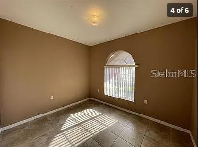 An empty room with tan walls, tile flooring, and an arched window with vertical blinds — 13102 INDIAN CREEK DRIVE UNIT 0, POINCIANA, FL