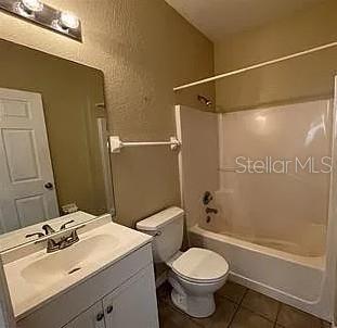 A bathroom features a white vanity, a toilet, and a shower-tub combination with beige walls — 13102 INDIAN CREEK DRIVE UNIT 0, POINCIANA, FL