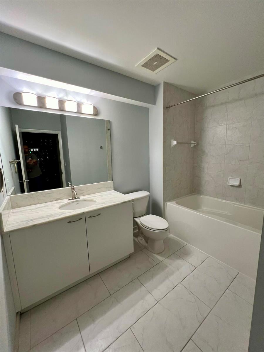 A bathroom features a white vanity with a marble countertop, a toilet, and a tub — 133 NE 2nd Avenue # 1006, Miami FL 33132, MIAMI, FL