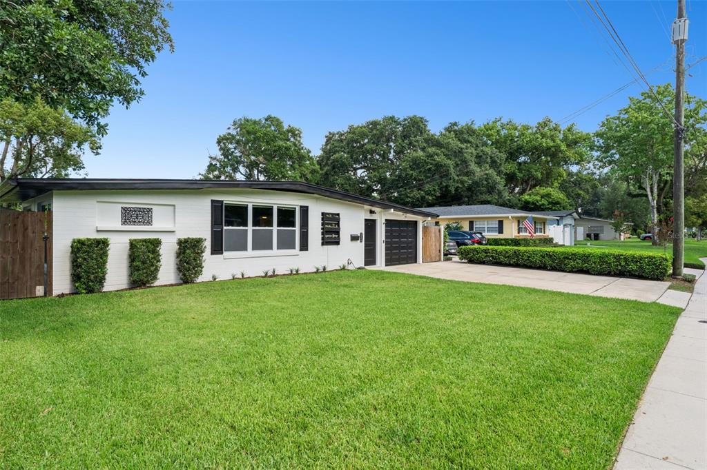 A white, single-story ranch-style house with a black garage door and a large front lawn — 526 N HAMPTON AVENUE, ORLANDO, FL