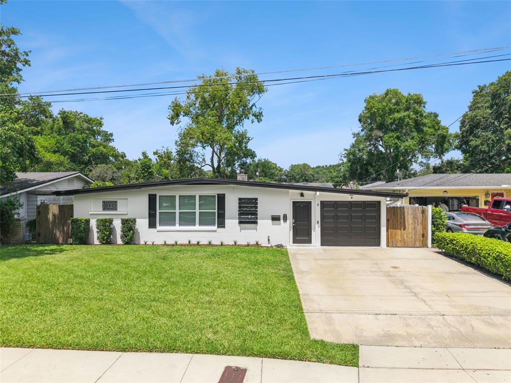 A single-story white brick house with a dark garage door and a front lawn — 526 N HAMPTON AVENUE, ORLANDO, FL
