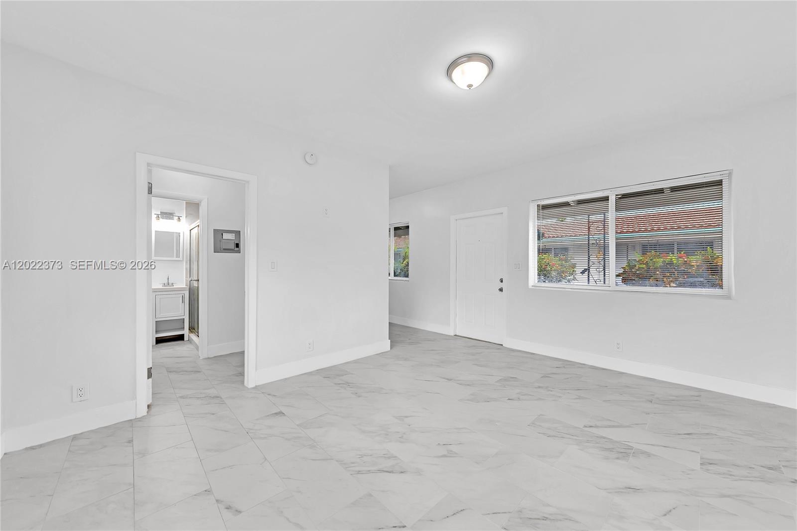 An empty room features white walls, marble-patterned tile flooring, a ceiling light, and a doorway — 1839 Funston St # 6, Hollywood FL 33020, HOLLYWOOD, FL
