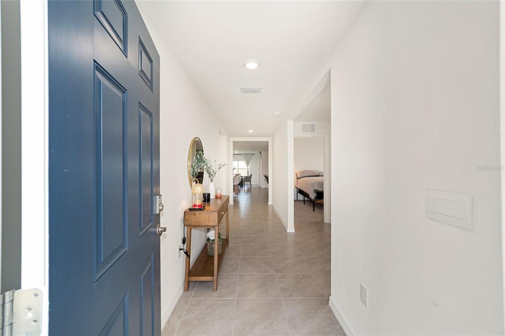 A view from an open blue front door into a tiled entryway hallway — 7199 SW 135TH PLACE, OCALA, FL