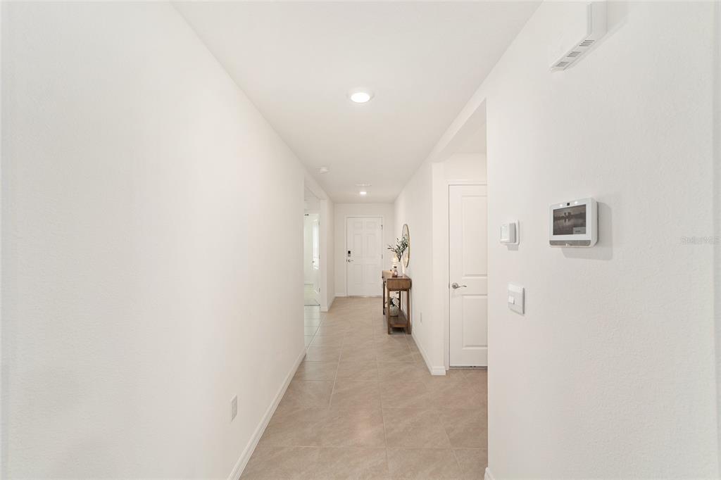 A bright hallway features light-colored tile flooring, white walls, and a view toward the entrance — 7199 SW 135TH PLACE, OCALA, FL
