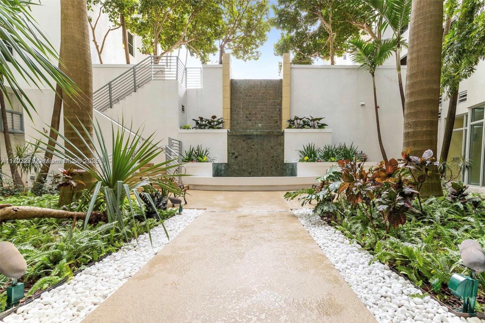 A stone waterfall feature serves as the focal point of a landscaped outdoor courtyard — 1830 Radius Dr # 421, Hollywood FL 33020, HOLLYWOOD, FL