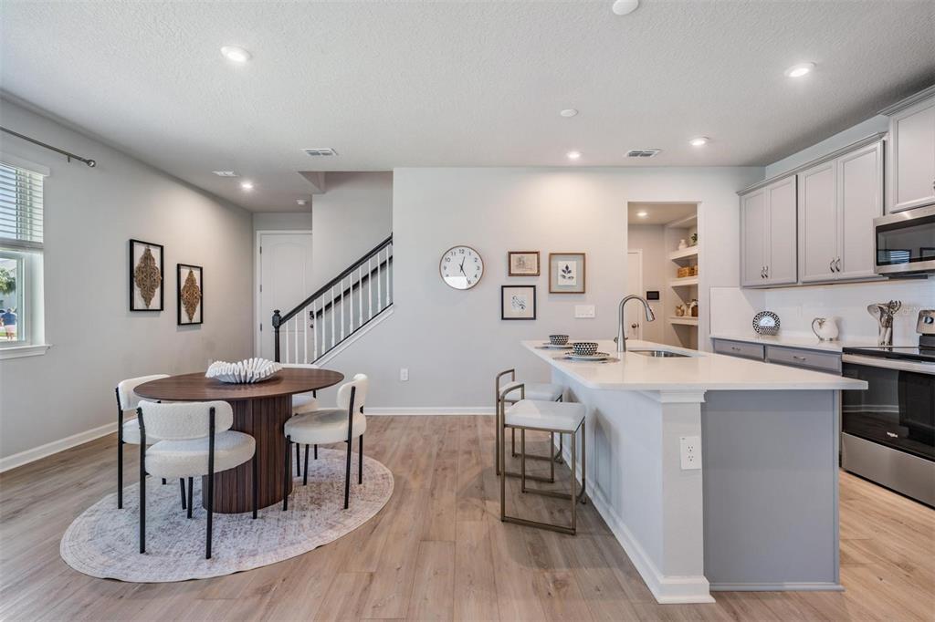 A kitchen with a center island and dining area featuring light wood floors and stairs — 19219 BLUE POND DRIVE, LUTZ, FL