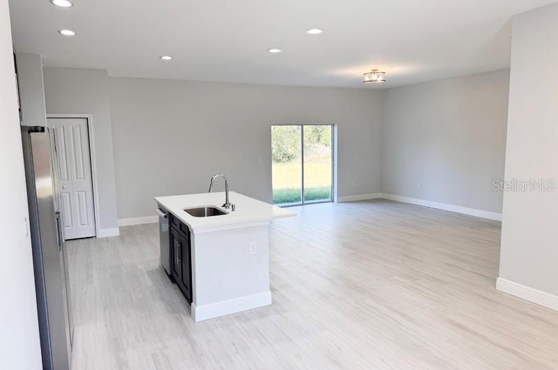 A kitchen island with a sink sits in an open-concept room with light flooring — 1153 CHALMER TERRACE, PORT CHARLOTTE, FL