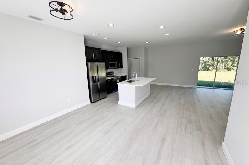 An open-concept kitchen features dark cabinetry, stainless steel appliances, and a white center island — 1153 CHALMER TERRACE, PORT CHARLOTTE, FL