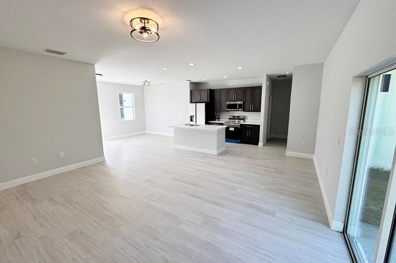 An open-concept kitchen with dark cabinets and a central island overlooks a spacious living area — 1153 CHALMER TERRACE, PORT CHARLOTTE, FL