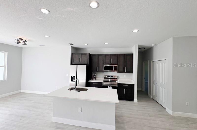 A kitchen features dark wood cabinets, stainless steel appliances, and a white quartz island — 1153 CHALMER TERRACE, PORT CHARLOTTE, FL