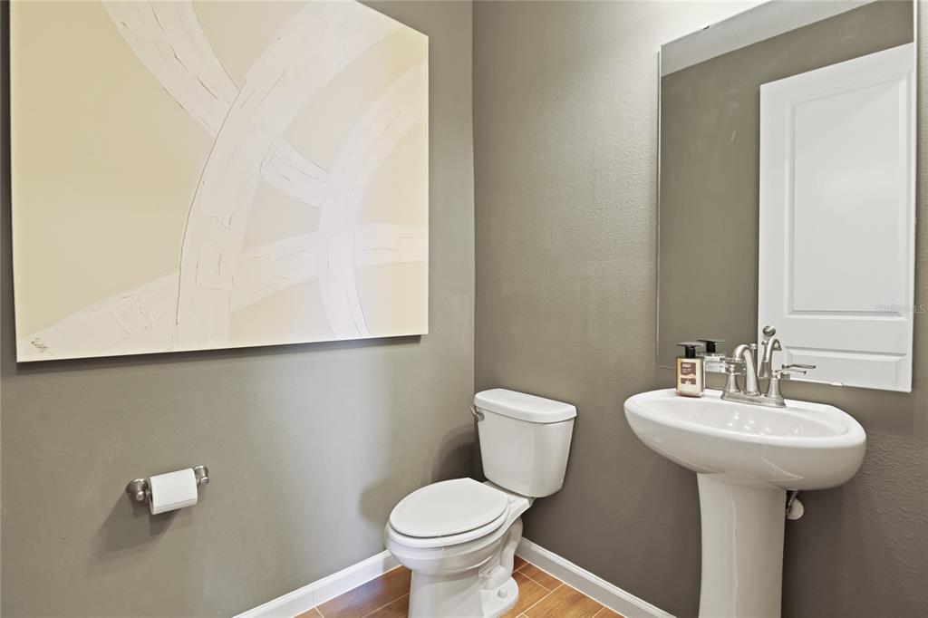 A powder room features a pedestal sink, a toilet, and abstract wall art — 2521 29TH LANE E, PALMETTO, FL
