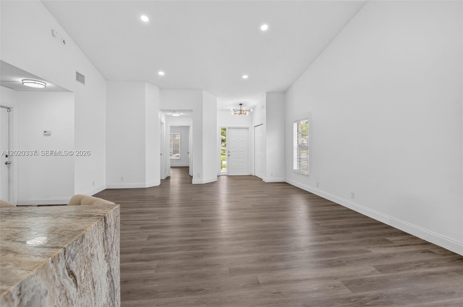 An empty living area features white walls, recessed lighting, and wood-look flooring — 9912 S 61st Way S # A, Boynton Beach FL 33437, BOYNTON BEACH, FL