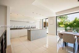 A modern kitchen with a central island and dining area opens to an outdoor patio — 41 route des breguieres, CT 06110, CT