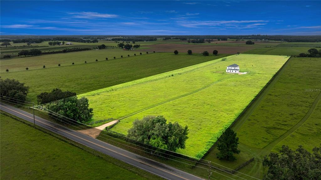 An aerial view shows a white house situated in the middle of a large field — 21786 NW 27TH STREET, MORRISTON, FL