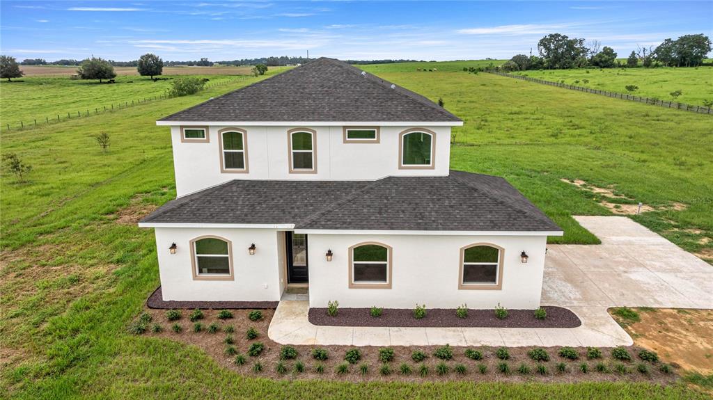 An aerial view of a two-story white stucco house with a dark shingled roof — 21786 NW 27TH STREET, MORRISTON, FL