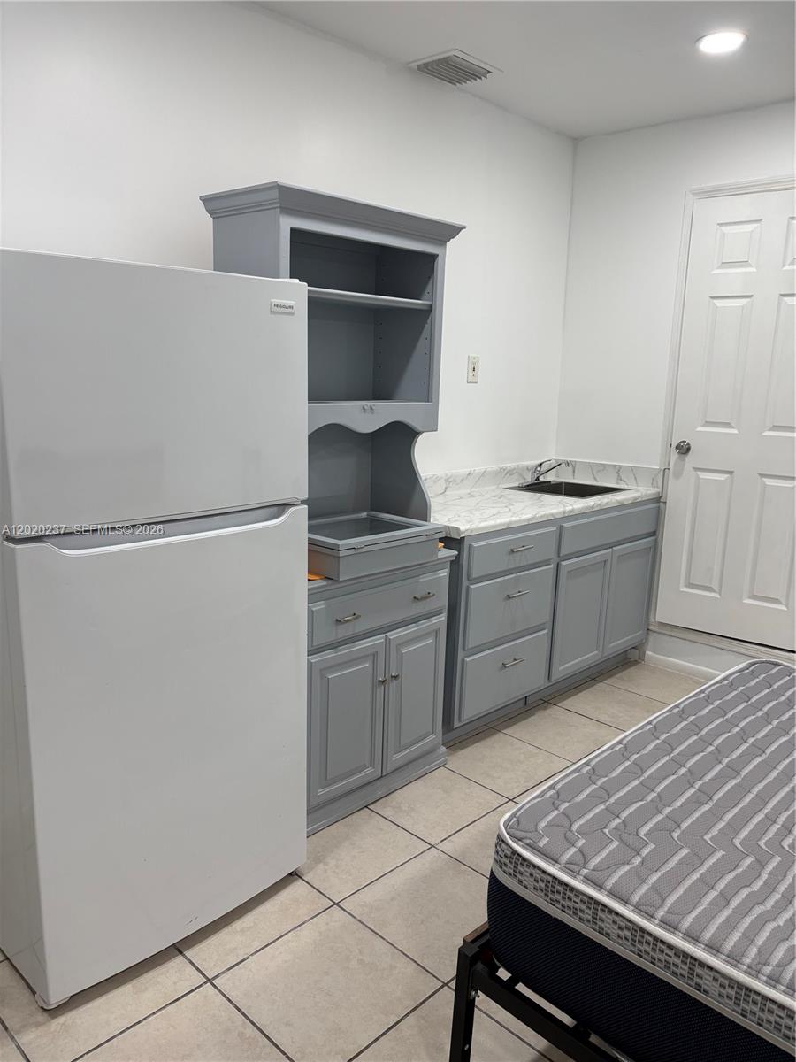 A small kitchenette features gray cabinets, a white refrigerator, and a marble-patterned countertop — 15844 SW 82nd St # b, Miami FL 33193, MIAMI, FL