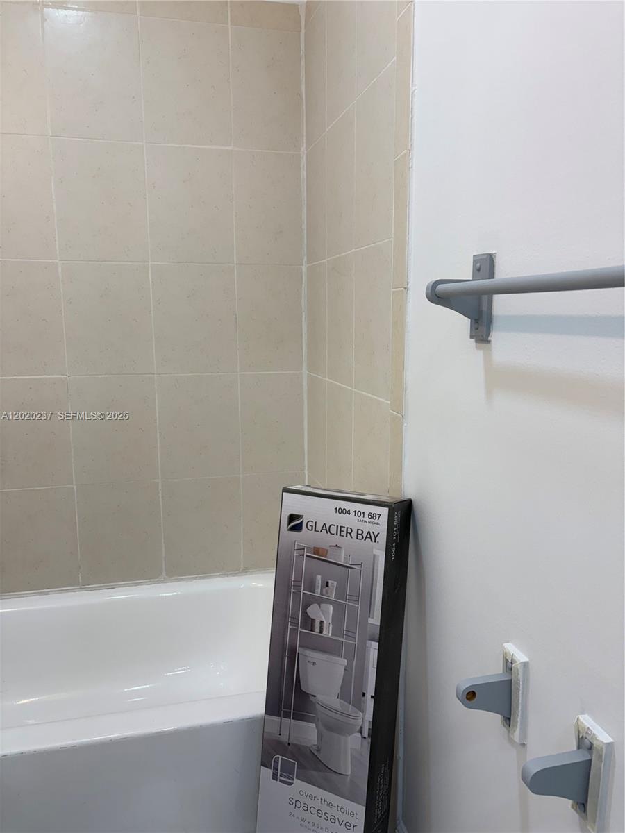 A bathroom features a tiled shower surround, a white bathtub, and an unassembled storage unit — 15844 SW 82nd St # b, Miami FL 33193, MIAMI, FL