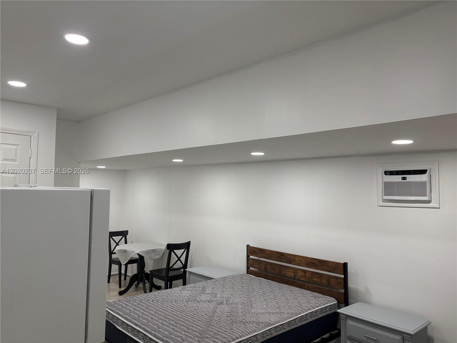 A bedroom features a bed, a small dining table, and a wall-mounted air conditioning unit — 15844 SW 82nd St # b, Miami FL 33193, MIAMI, FL