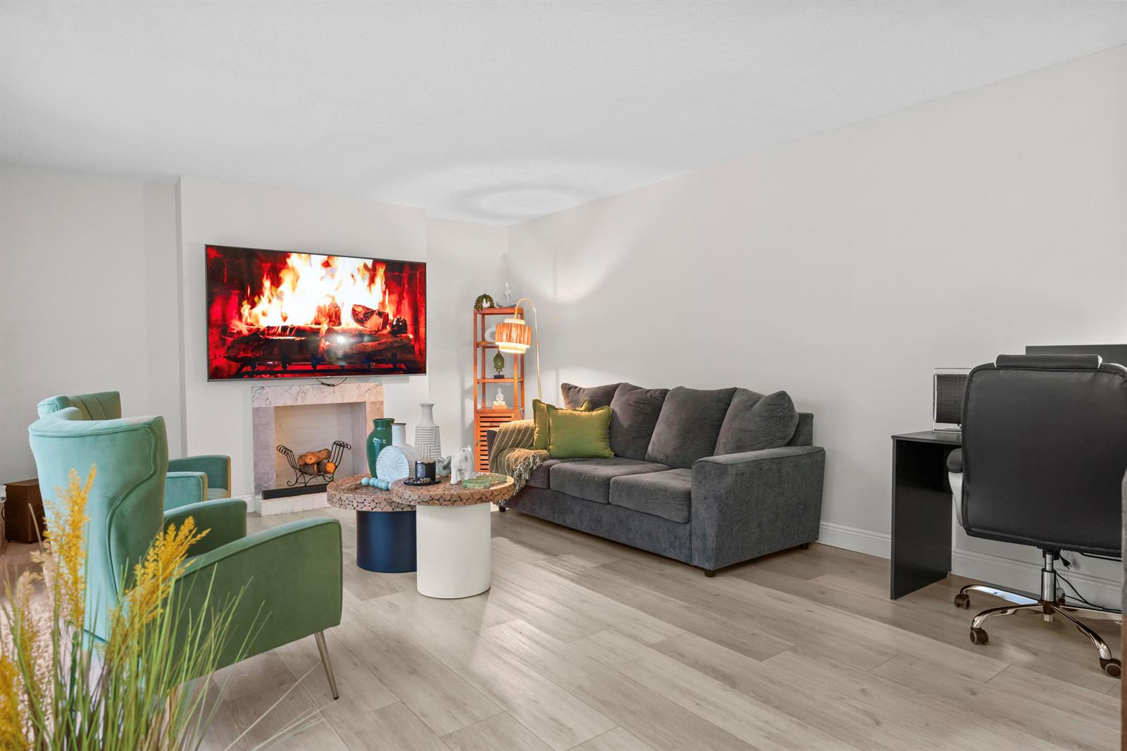 A living room features a fireplace with a mounted television, a sofa, and green armchairs — 1630 Forest Lakes Circle # C, West Palm Beach FL 33406, WEST PALM BEACH, FL