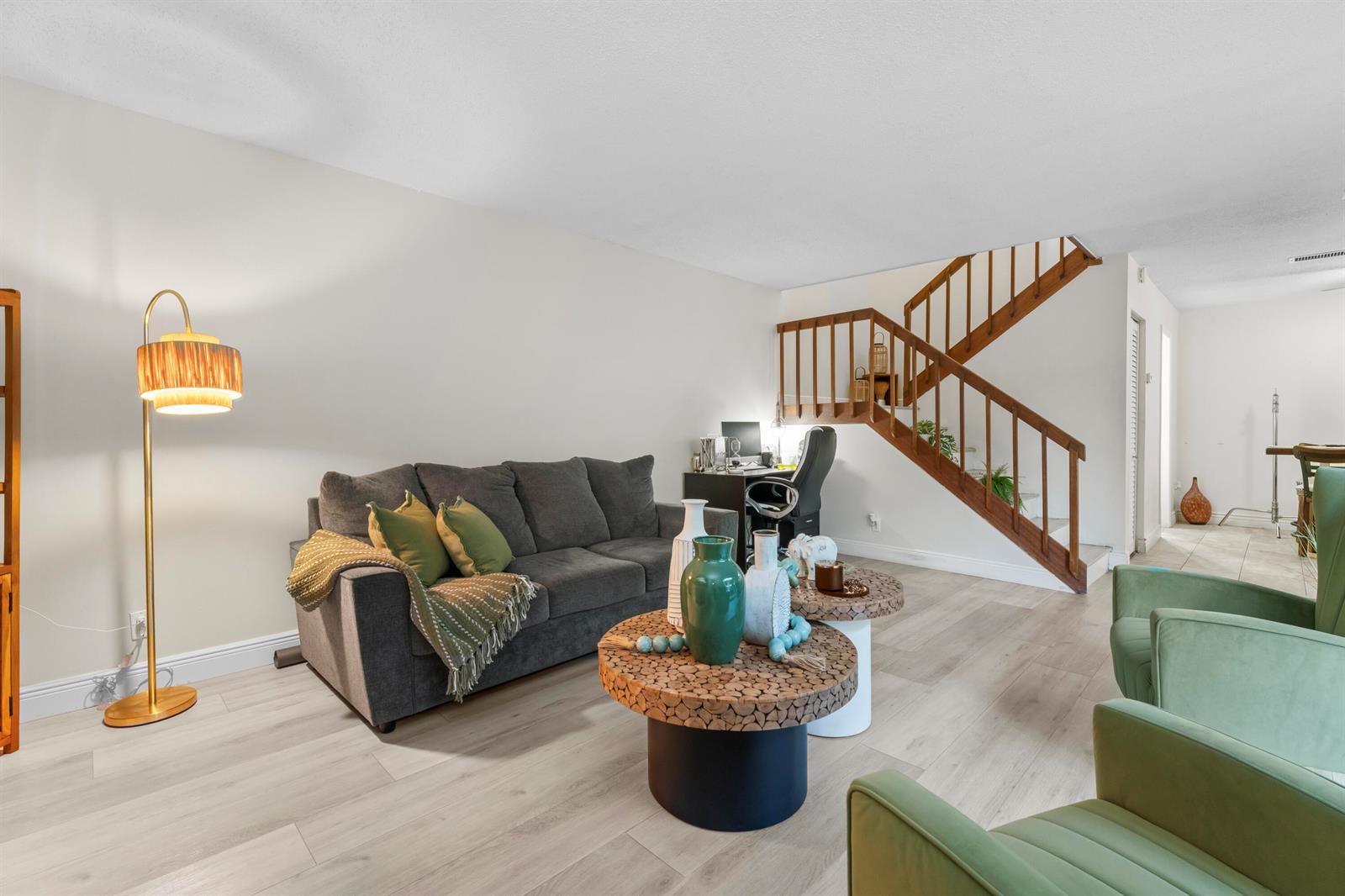 A living room with a grey sofa, two green armchairs, wood-topped tables, and a staircase — 1630 Forest Lakes Circle # C, West Palm Beach FL 33406, WEST PALM BEACH, FL