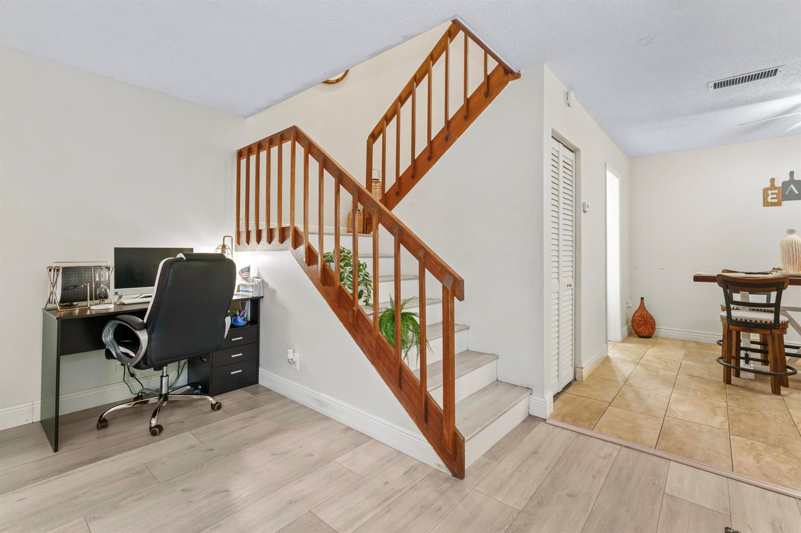 A room features a wooden staircase, a desk with a computer, and tiled dining area — 1630 Forest Lakes Circle # C, West Palm Beach FL 33406, WEST PALM BEACH, FL