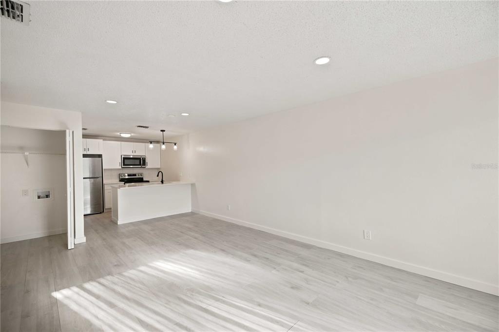 An open-concept living area features light wood-look flooring and a kitchen with white cabinetry — 5395 SE 30TH PLACE ALL UNITS, OCALA, FL