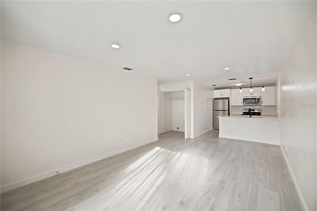 An open-concept living area with light wood-look flooring leads to a modern white kitchen — 5395 SE 30TH PLACE ALL UNITS, OCALA, FL