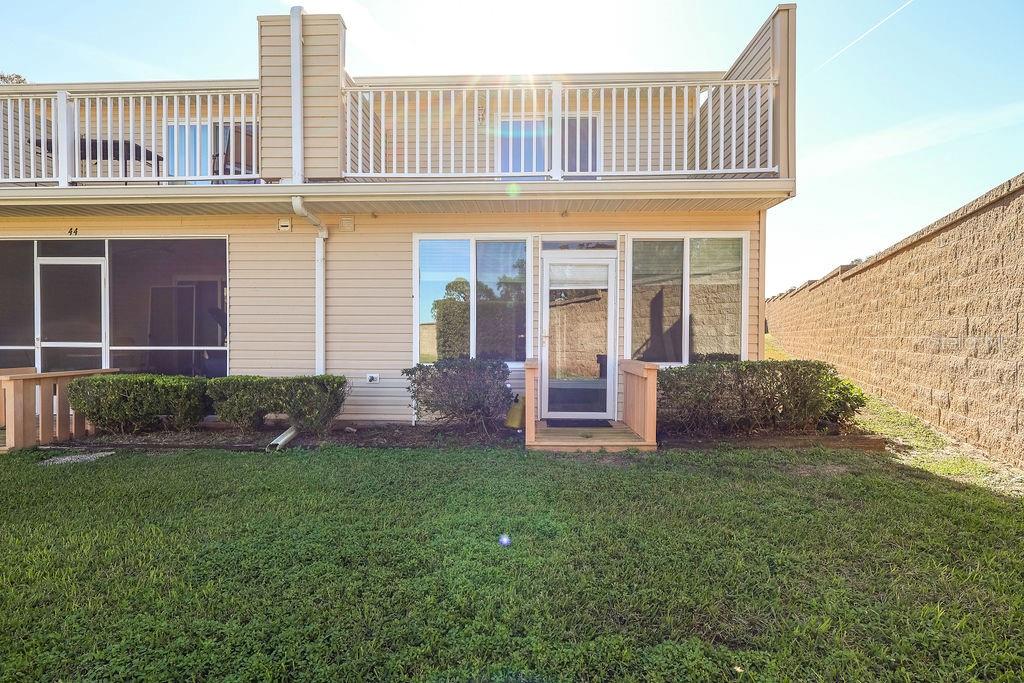 A two-story townhouse exterior features a screened patio, a small wooden deck, and a balcony — 11001 SE SUNSET HARBOR ROAD UNIT F45, SUMMERFIELD, FL