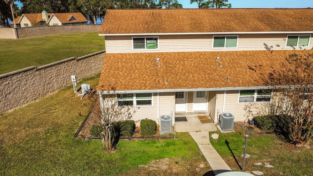 An aerial view of a two-story duplex with tan siding and a brown shingled roof — 11001 SE SUNSET HARBOR ROAD UNIT F45, SUMMERFIELD, FL