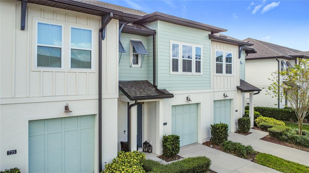A row of multi-story townhomes features light-colored siding, light green garage doors, and small landscaping — 721 BENOI DR, DAVENPORT, FL