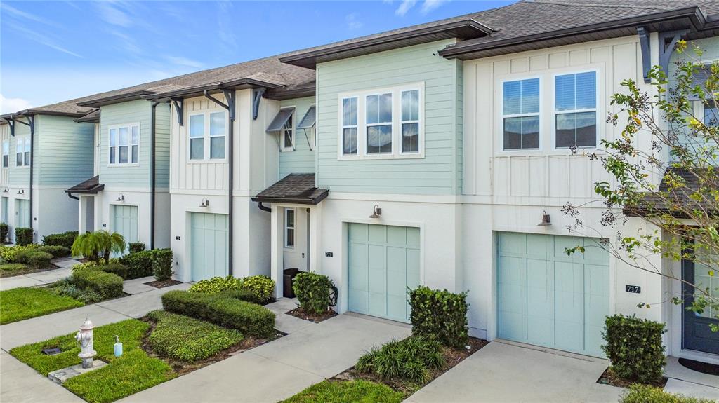 An exterior view of a row of multi-story townhomes with light blue garages and siding — 721 BENOI DR, DAVENPORT, FL