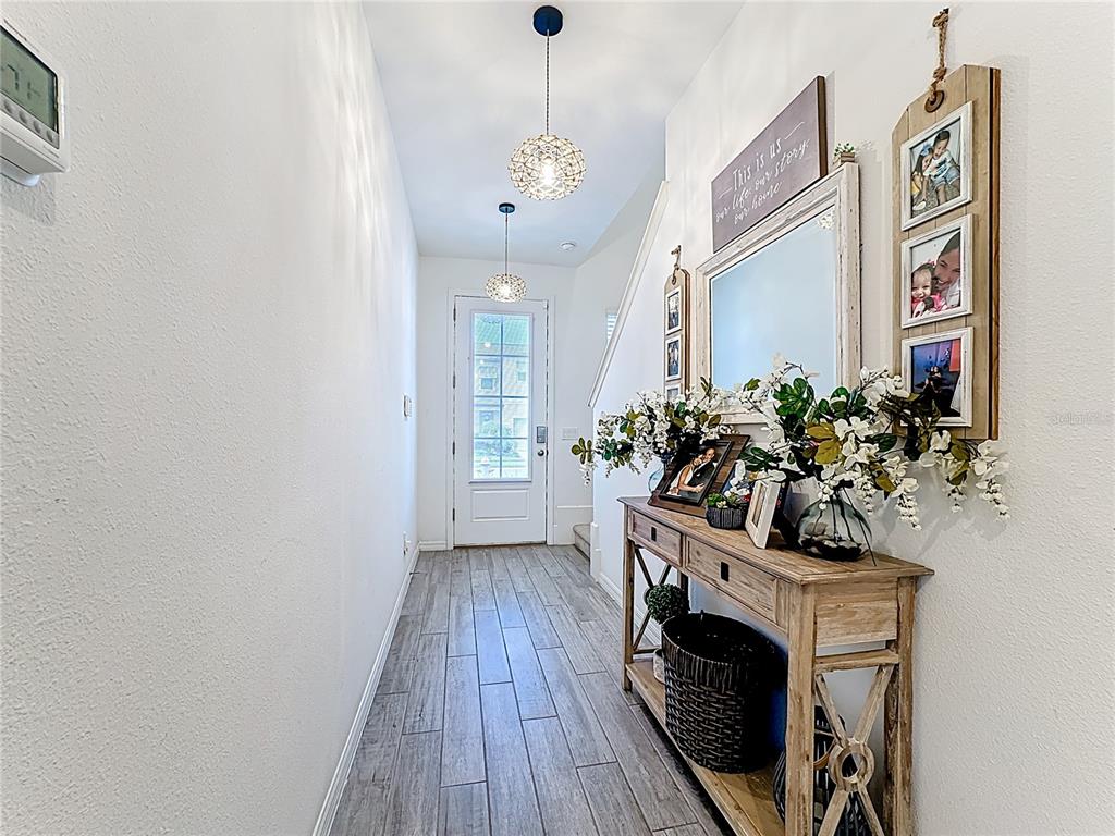 A bright entryway features a wooden console table, a mirror, and two hanging globe lights — 721 BENOI DR, DAVENPORT, FL