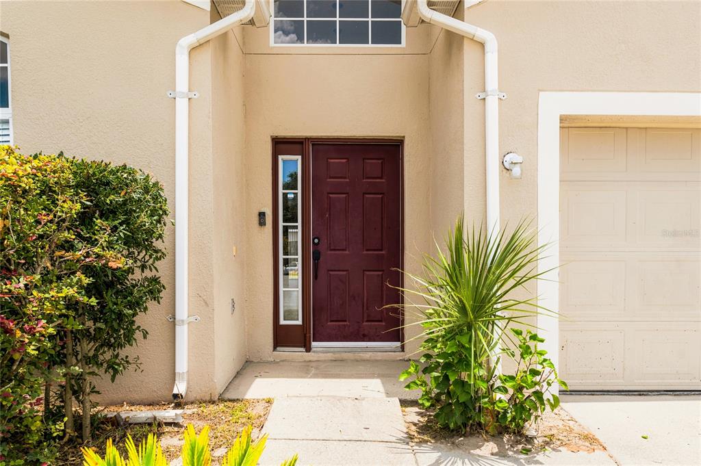 The exterior of a home features a maroon front door, a side light, and a garage — 2572 ACUNA COURT, LAKE MARY, FL