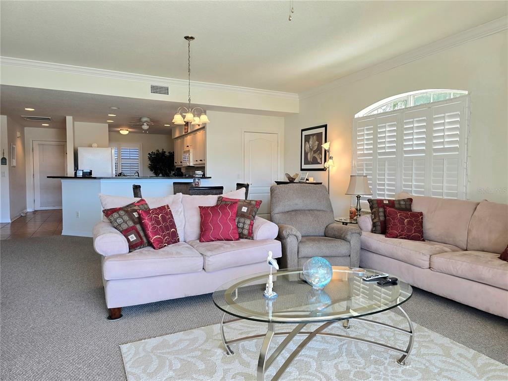 A living room features a light-colored sofa, a recliner, and a glass coffee table — 6446 7TH AVENUE CIRCLE W UNIT 6446, BRADENTON, FL