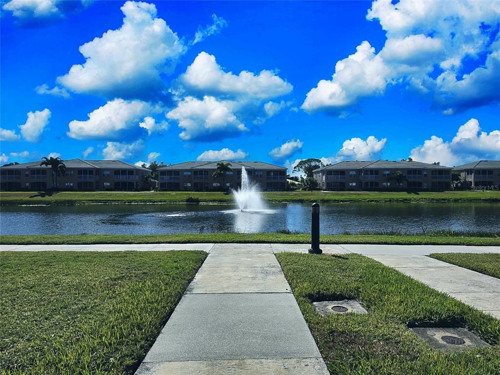 A sidewalk leads toward a pond with a fountain in front of several apartment buildings — 6446 7TH AVENUE CIRCLE W UNIT 6446, BRADENTON, FL