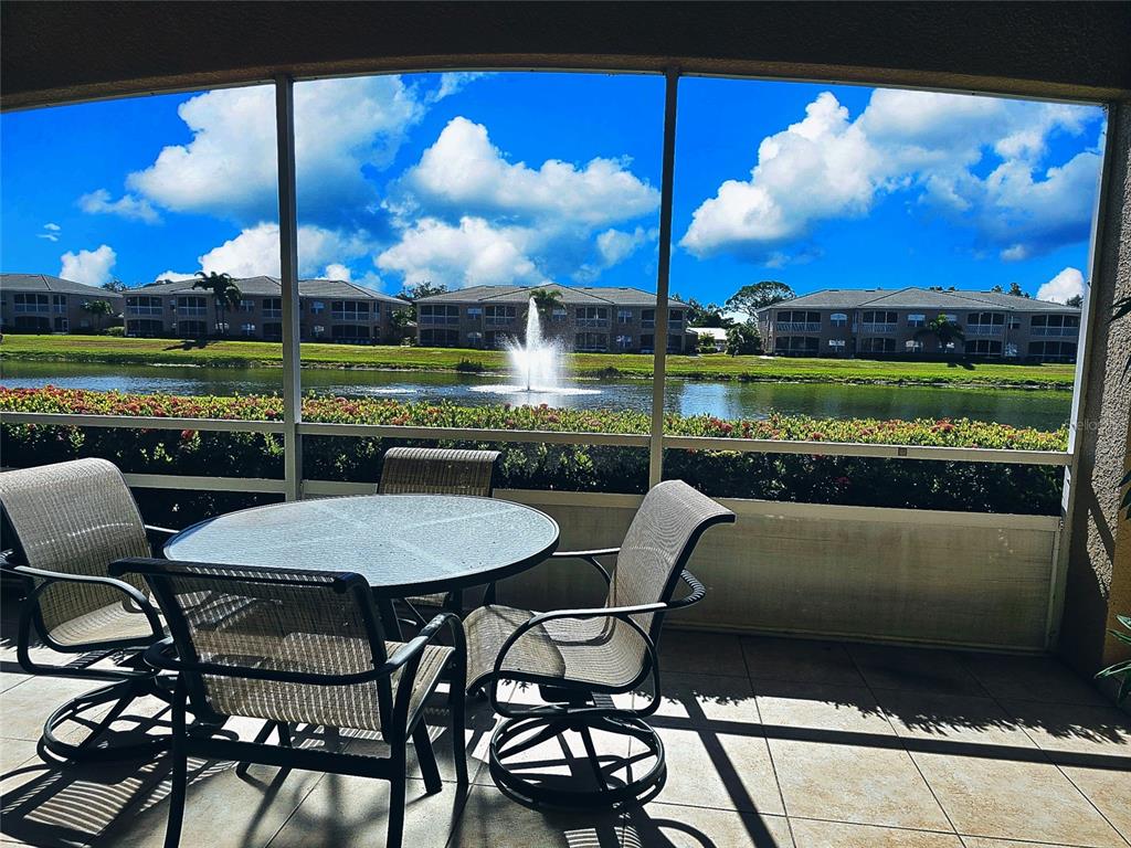 A screened-in patio features a dining set overlooking a pond with a fountain — 6446 7TH AVENUE CIRCLE W UNIT 6446, BRADENTON, FL