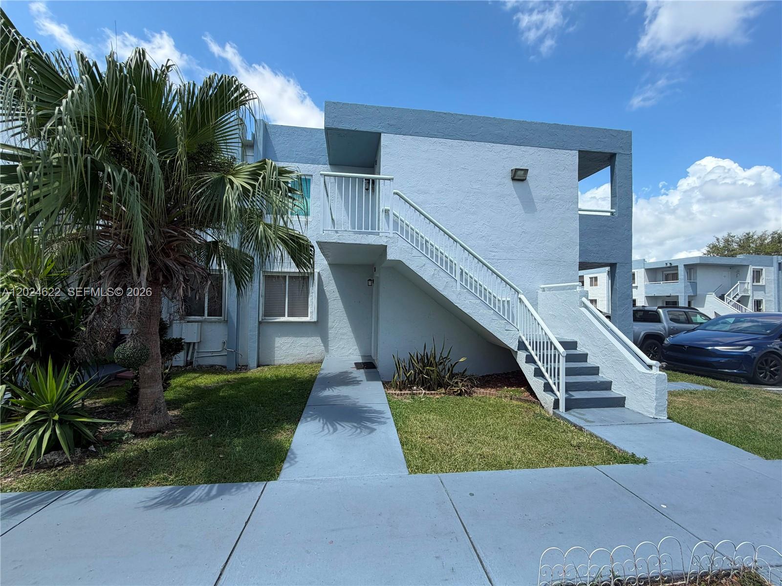 An exterior view of a two-story blue apartment building with an outdoor staircase — 6207 SW 131st Ct # 101, Miami FL 33183, MIAMI, FL