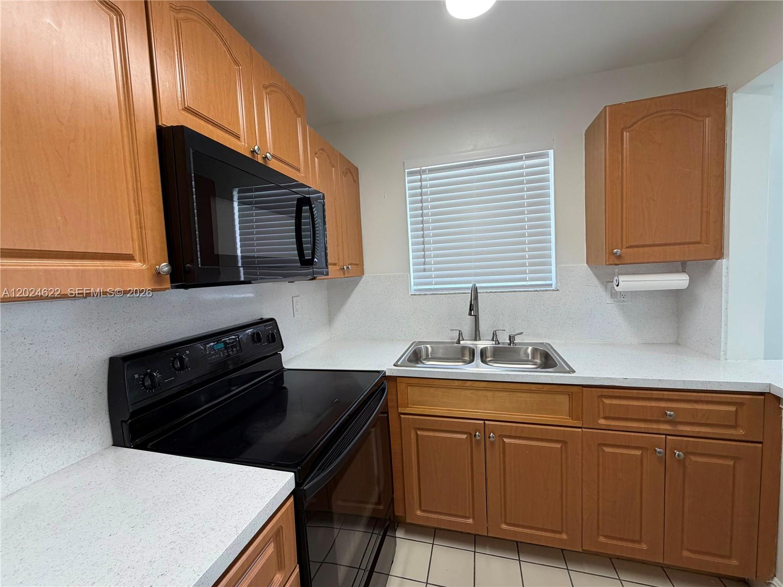 A kitchen features light wood cabinets, black appliances, a double sink, and white countertops — 6207 SW 131st Ct # 101, Miami FL 33183, MIAMI, FL