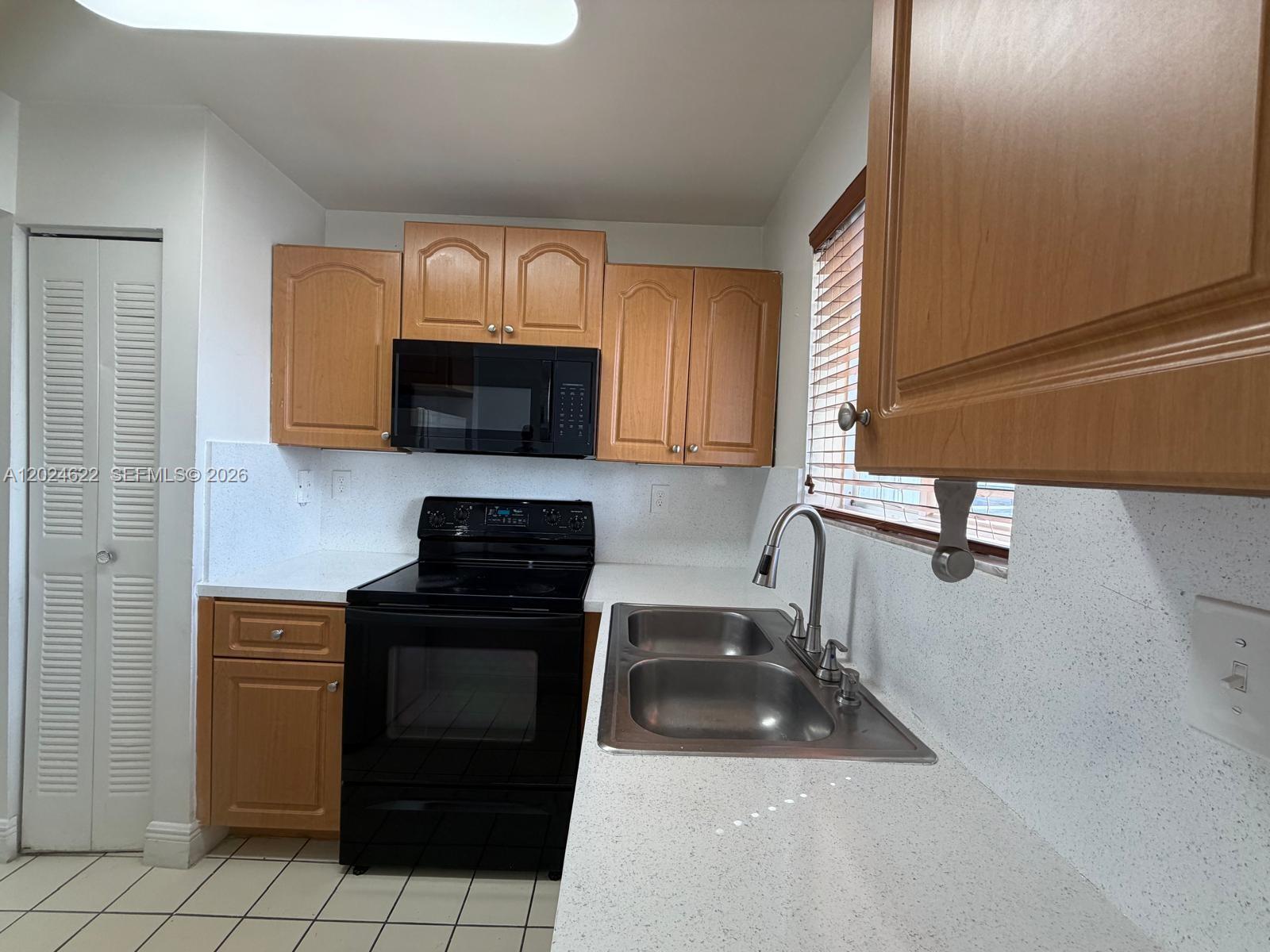 A kitchen features wood cabinets, black appliances, a double sink, and white speckled countertops — 6207 SW 131st Ct # 101, Miami FL 33183, MIAMI, FL