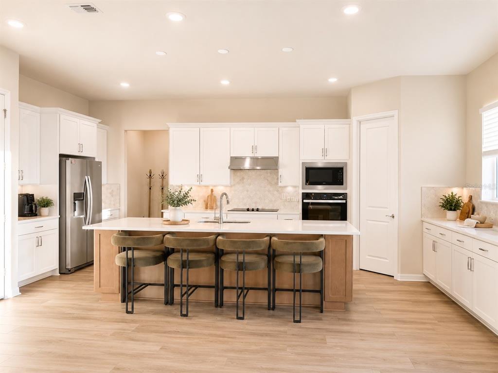 A modern kitchen features white cabinetry, a large wooden island with four stools, and stainless appliances — 4330 SUNSET PRESERVE BLVD, ORLANDO, FL