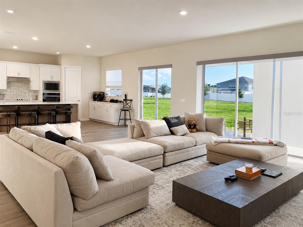 A spacious living room with a large sectional sofa, coffee table, and open kitchen area — 4330 SUNSET PRESERVE BLVD, ORLANDO, FL