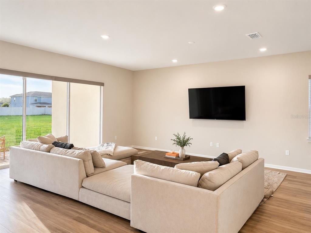A living room features a large beige sectional sofa, a coffee table, and a wall-mounted television — 4330 SUNSET PRESERVE BLVD, ORLANDO, FL