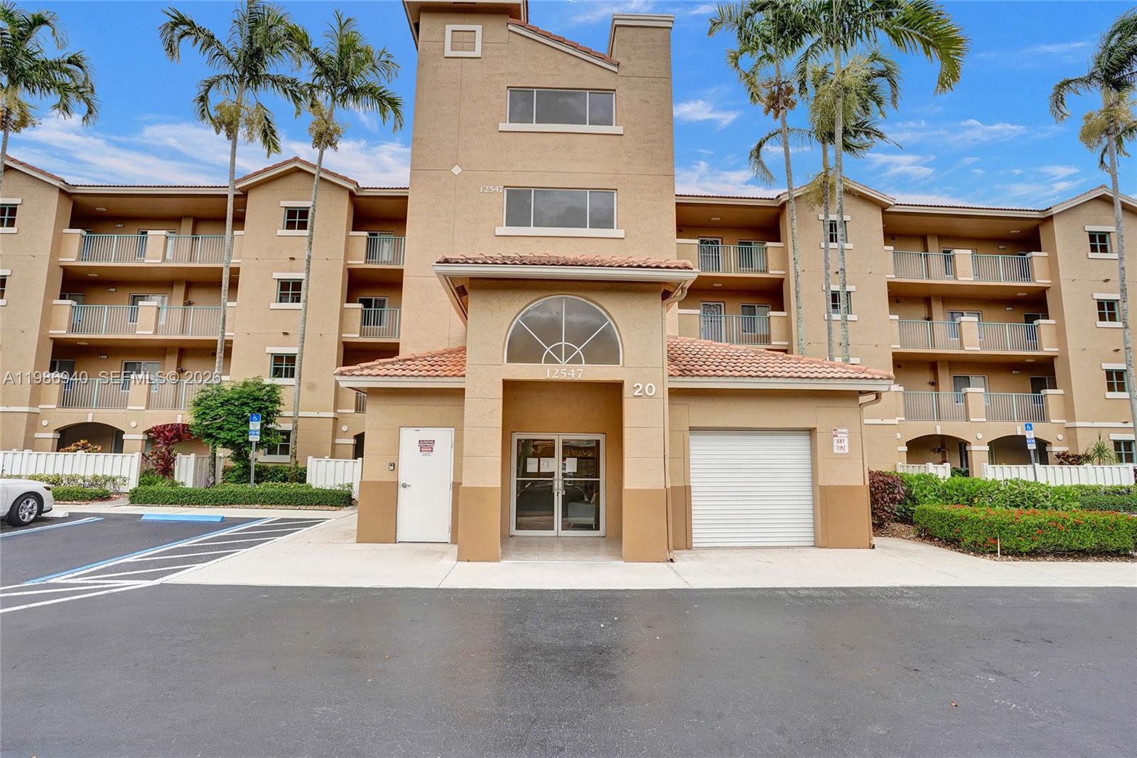 A multi-story tan apartment building features balconies and a parking lot with several cars — 12547 Imperial Isle Dr # 206, Boynton Beach FL 33437, BOYNTON BEACH, FL