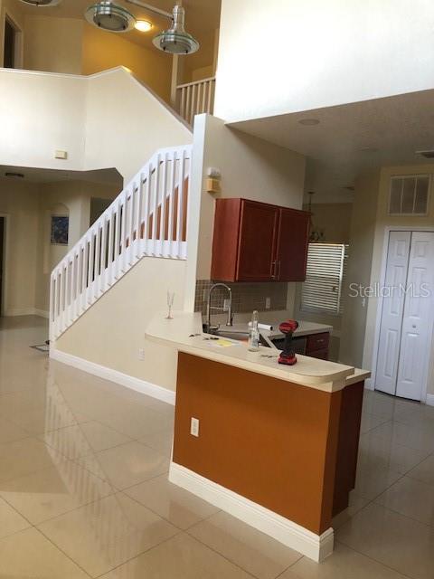 A two-story yellow house features a recessed entryway, palm trees, and dark mulch landscaping — 5359 DAHLIA RESERVE DRIVE, KISSIMMEE, FL