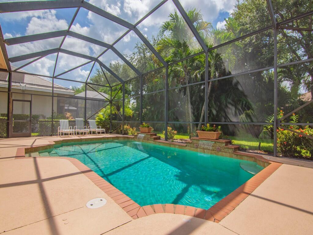 A screened-in swimming pool with a brick border and two water features on a patio — 1225 Riverwind Circle, Vero Beach FL 32967, VERO BEACH, FL
